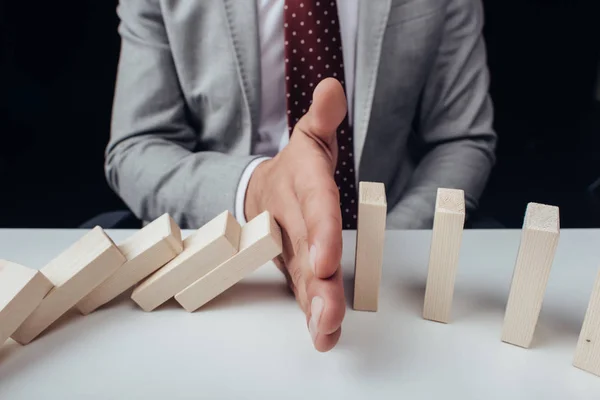 Close up view of businessman preventing wooden blocks from falling — Stock Photo