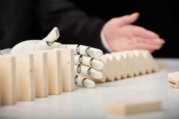 Partial view of woman pushing wooden bricks while robotic hand preventing row from falling — Stock Photo