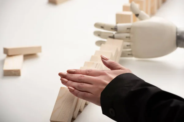 Vista parziale della donna spingendo mattoni di legno mentre la mano robotica impedisce alla fila di cadere — Foto stock