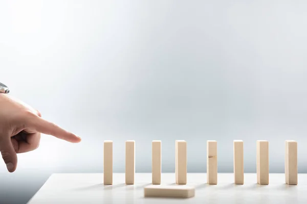 Cropped view of man pointing with finger at wooden block row on white background — Stock Photo