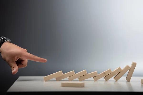 Abgeschnittene Ansicht eines Mannes, der mit dem Finger auf umgestürzte Holzblockreihe auf grauem Hintergrund zeigt — Stockfoto