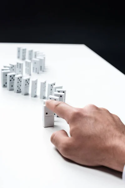 Partial view of man pointing at domino row on white table — Stock Photo