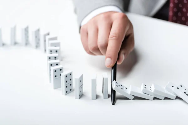 Close up view of man preventing dominoes from falling with pen — Stock Photo
