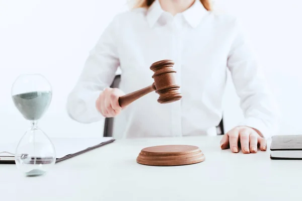 Selektiver Fokus der Richterin mit Hammer in der Hand in der Nähe der Sanduhr mit fließendem Sand isoliert auf weiß — Stockfoto