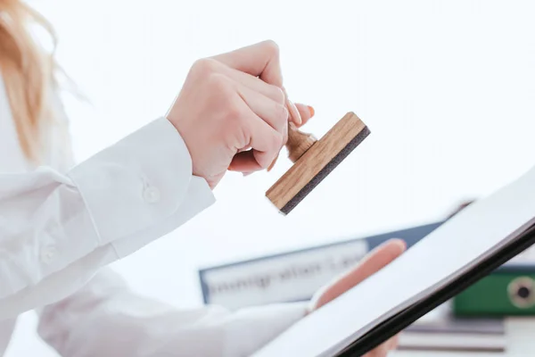 Selective focus of female lawyer holding clipboard and stamp in hands isolated on white — Stock Photo