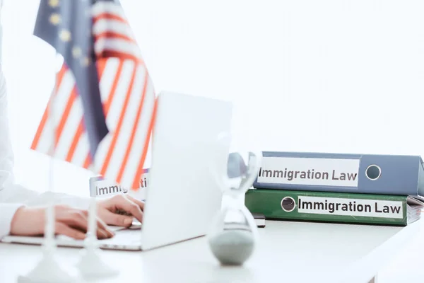 Selective focus of woman typing on laptop near hourglass and american flag — Stock Photo