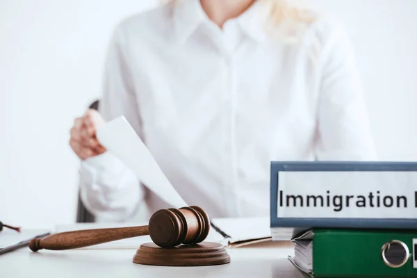 Selective focus of gavel near folders with immigration law lettering with woman on background isolated on white — Stock Photo