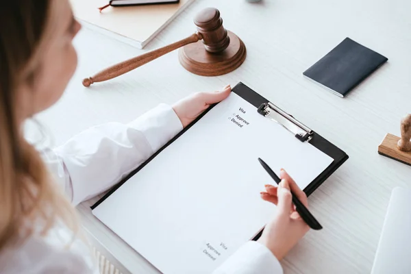 Cropped view of woman holding clipboard with document near gavel — Stock Photo