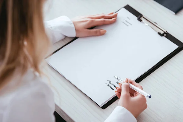 Foyer sélectif de la femme mettant signe de contrôle sur le document avec lettrage — Photo de stock