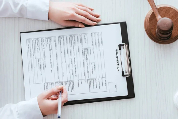 Top view of woman holding pen near document with visa application lettering — Stock Photo