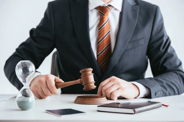 Selective focus of man in suit holding gavel near hourglass  isolated on white — Stock Photo