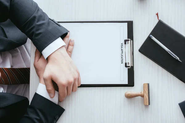 Top view of male hands near clipboard with immigration lettering on document — Stock Photo