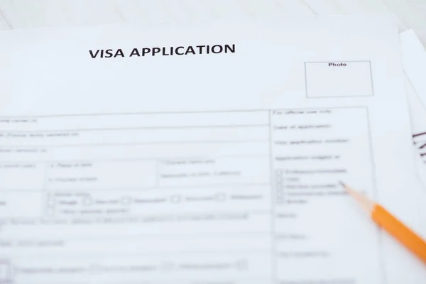 Enfoque selectivo de la inscripción de la solicitud de visado en el documento cerca del lápiz de madera - foto de stock