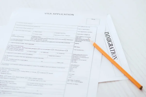 Selective focus of  wooden pencil near document with visa application and immigration lettering — Stock Photo