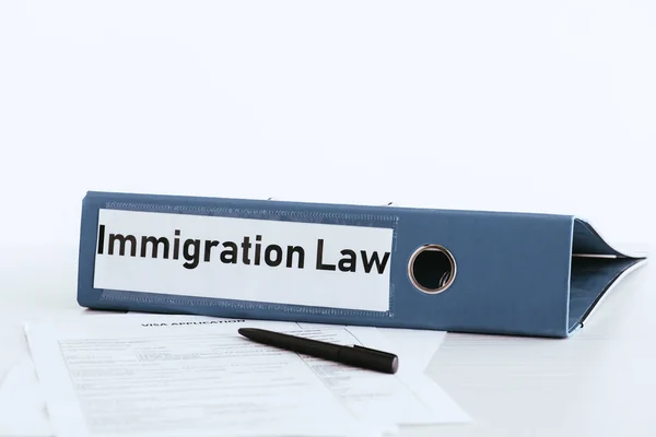 Enfoque selectivo de la carpeta con letras de la ley de inmigración cerca de documentos y pluma - foto de stock