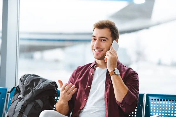 Smiling man talking on smartphone while waiting in waiting hall — Stock Photo