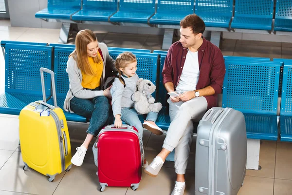 Overhead view of father looking at daughter near suitcases and wife in departure lounge — Stock Photo