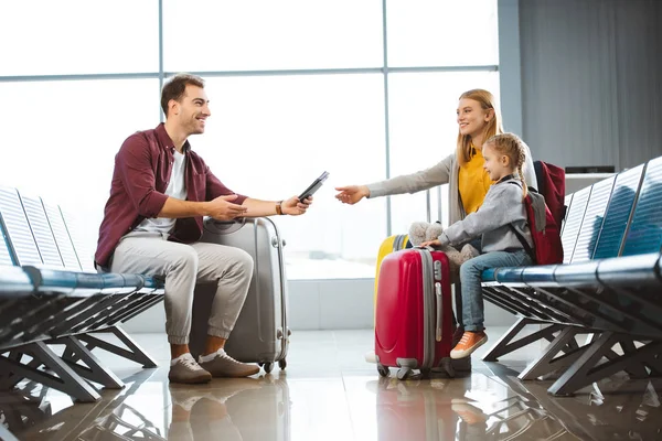 Красивий батька, даючи паспортів з авіаквитків до дружини поблизу дочка в аеропорту — стокове фото