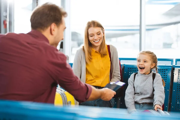 Enfoque selectivo de padre dando pasaportes con billetes de avión cerca de esposa e hija en el aeropuerto - foto de stock