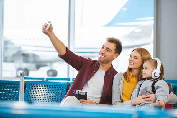 Familia feliz tomando selfie y sonriendo en la sala de salida - foto de stock