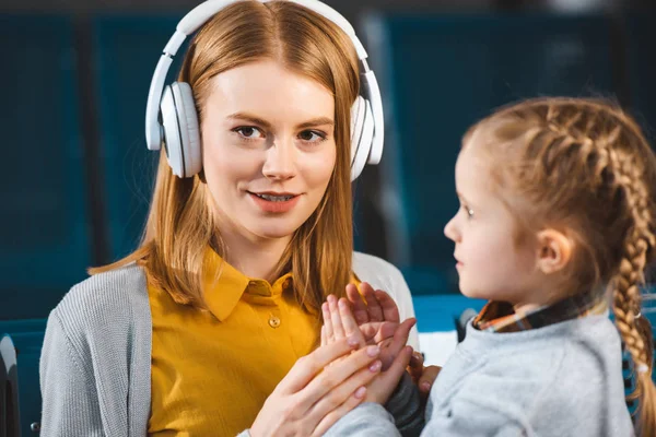 Enfoque selectivo de la atractiva madre escuchando música en auriculares cerca de la hija - foto de stock