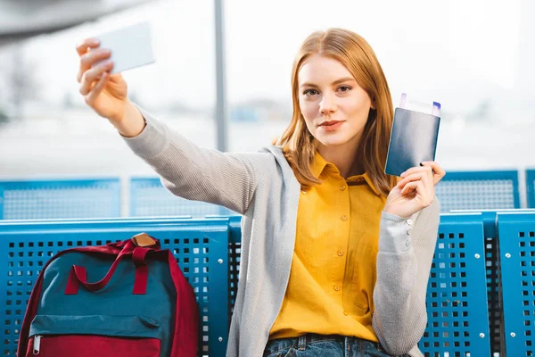Belle femme prenant selfie avec passeport et billet d'avion dans la salle d'attente — Photo de stock