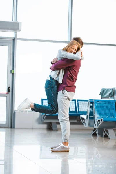 Felice donna abbracciare fidanzato in aeroporto — Foto stock