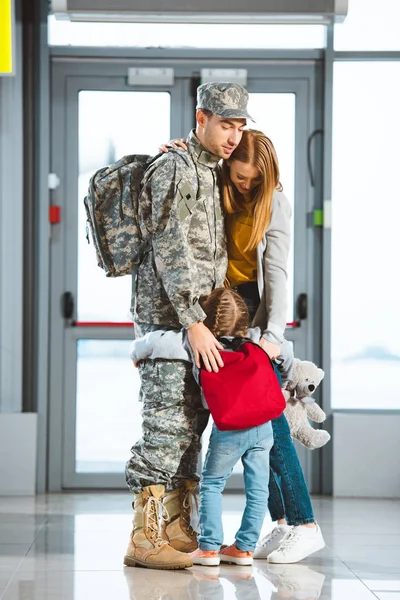 Figlia abbracciare mamma e papà in uniforme militare in aeroporto — Foto stock