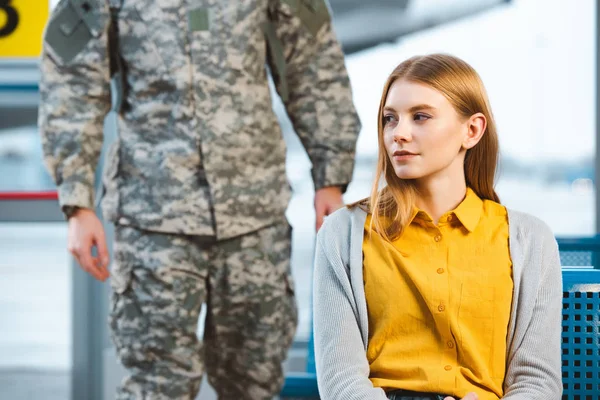 Привлекательная женщина сидит в аэропорту с ветераном на заднем плане — стоковое фото