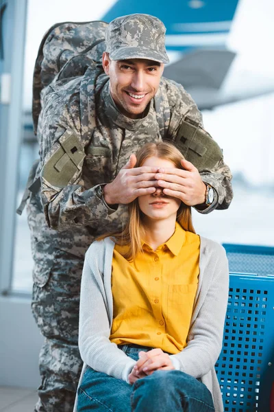 Handsome veteran in military uniform closing eyes of girlfriend — Stock Photo