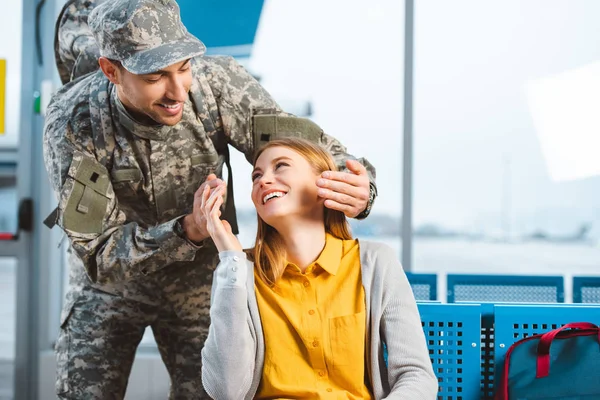 Bonito veterano olhando para alegre namorada no aeroporto — Fotografia de Stock