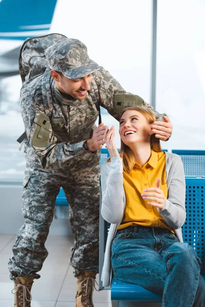 Веселый ветеран смотрит на удивленную девушку в аэропорту — стоковое фото