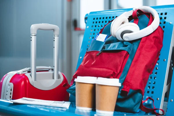 Навушники на рюкзак поблизу паперових стаканчиків і багажу в аеропорту — стокове фото