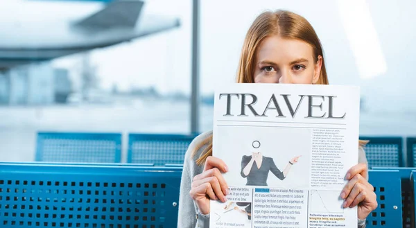 Mulher cobrindo rosto com jornal de viagem na sala de espera — Fotografia de Stock