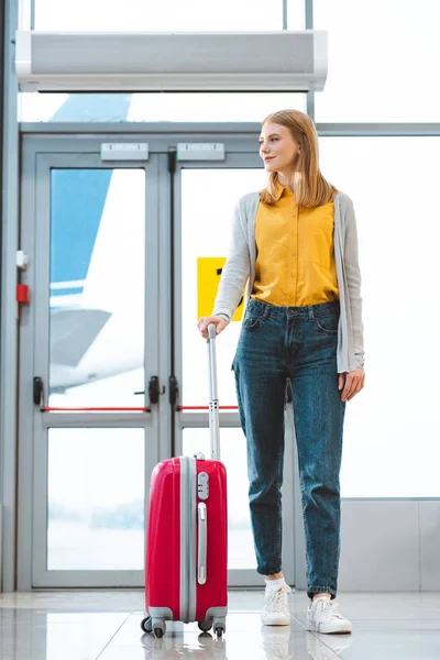 Attraente donna in piedi con bagaglio in aeroporto — Foto stock