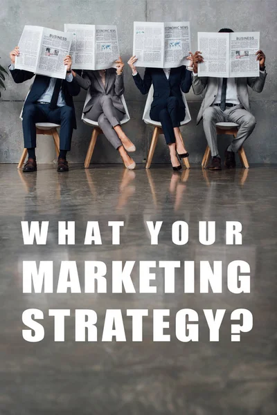 Businesspeople sitting on chairs and holding newspapers in front of faces in waiting hall with what your marketing strategy question on floor — Stock Photo