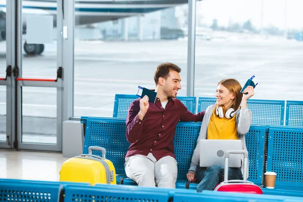 Парень и девушка держат паспорта и смотрят друг на друга в аэропорту — стоковое фото