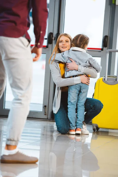 Enfoque selectivo de la madre abrazando hija cerca del marido en el aeropuerto - foto de stock