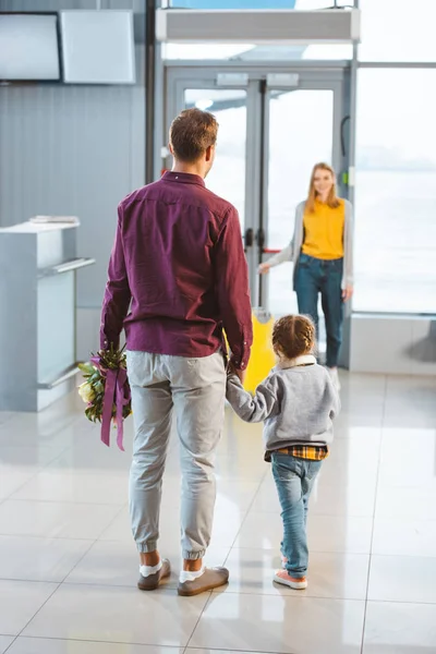 Enfoque selectivo del hombre cogido de la mano con la hija y mirando a la esposa con el equipaje - foto de stock