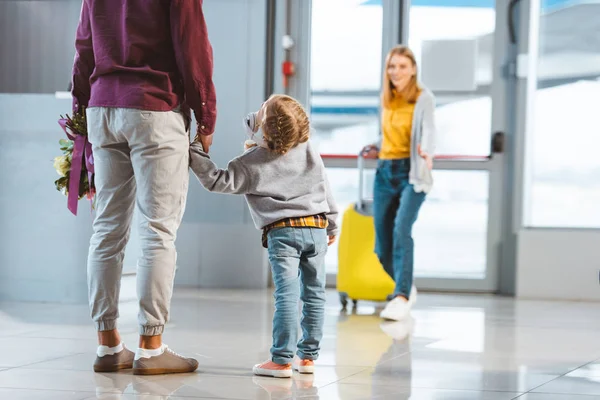 Selektiver Fokus des Kindes beim Händchenhalten mit Vater in der Nähe der Mutter mit Gepäck im Hintergrund — Stockfoto