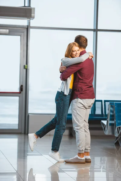 Atractiva mujer abrazando novio en sala de espera - foto de stock