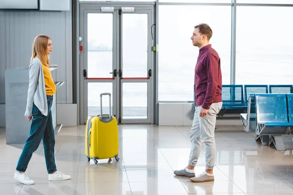 Handsome man looking at girlfriend in waiting hall of airport — Stock Photo