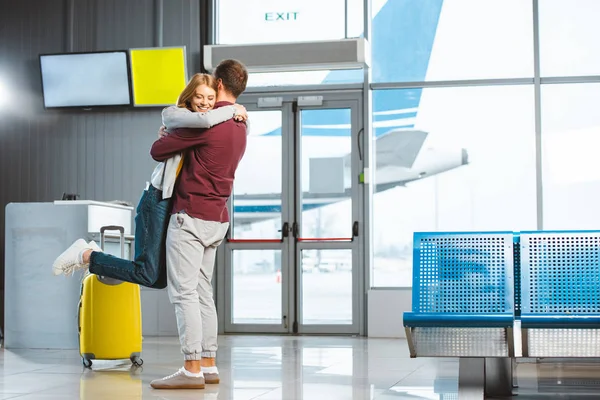 Beautiful woman hugging boyfriend in waiting hall near baggage — Stock Photo