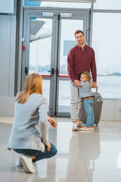 Селективное внимание милого ребенка обнимающего отца с чемоданом в аэропорту — стоковое фото