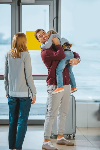 Happy father holding in arms daughter near wife in airport — Stock Photo