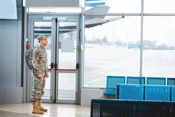 Veteran in military uniform standing with backpack in departure lounge — Stock Photo