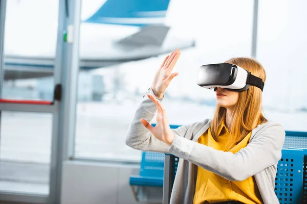 Mulher vestindo fone de ouvido realidade virtual enquanto sentado no aeroporto — Fotografia de Stock