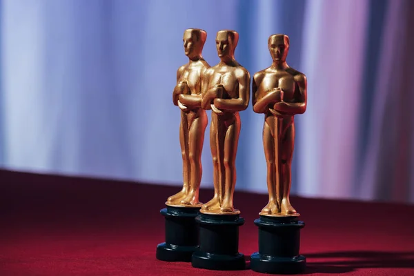 КИЕВ, УКРАИНА - 10 ЯНВАРЯ 2019 года: селективный фокус статуэток золотого Оскара на фиолетовом фоне — стоковое фото