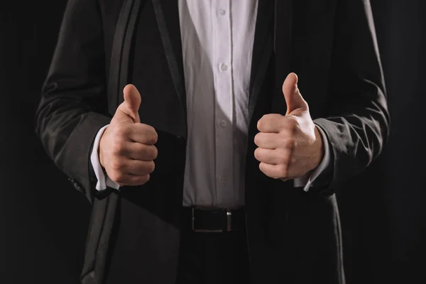 Hombre en ropa formal mostrando pulgares hacia arriba aislado en negro - foto de stock