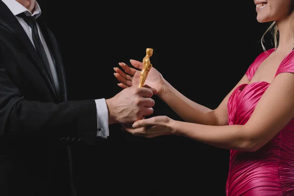 KYIV, UKRAINE - JANUARY 10, 2019: partial view of man giving oscar award to woman isolated on black — Stock Photo